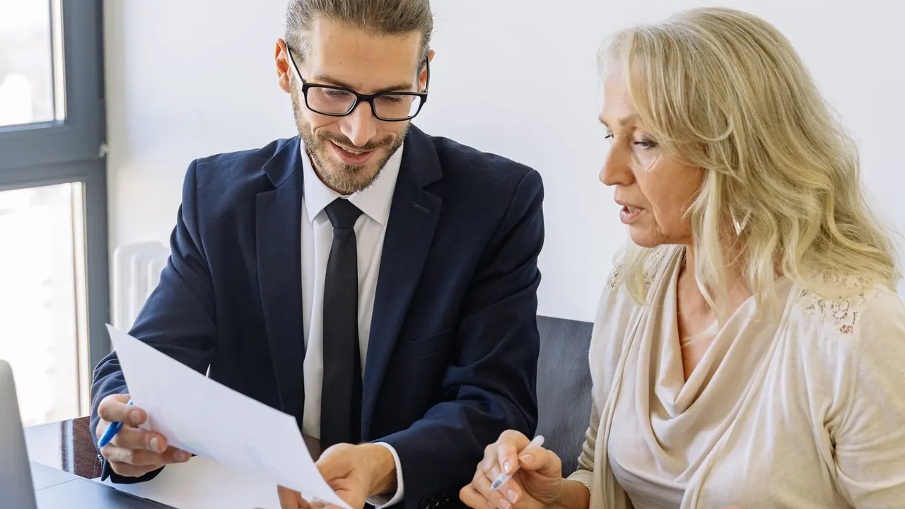 Business owner and financial advisor reviewing printed financial statements before selling the business.